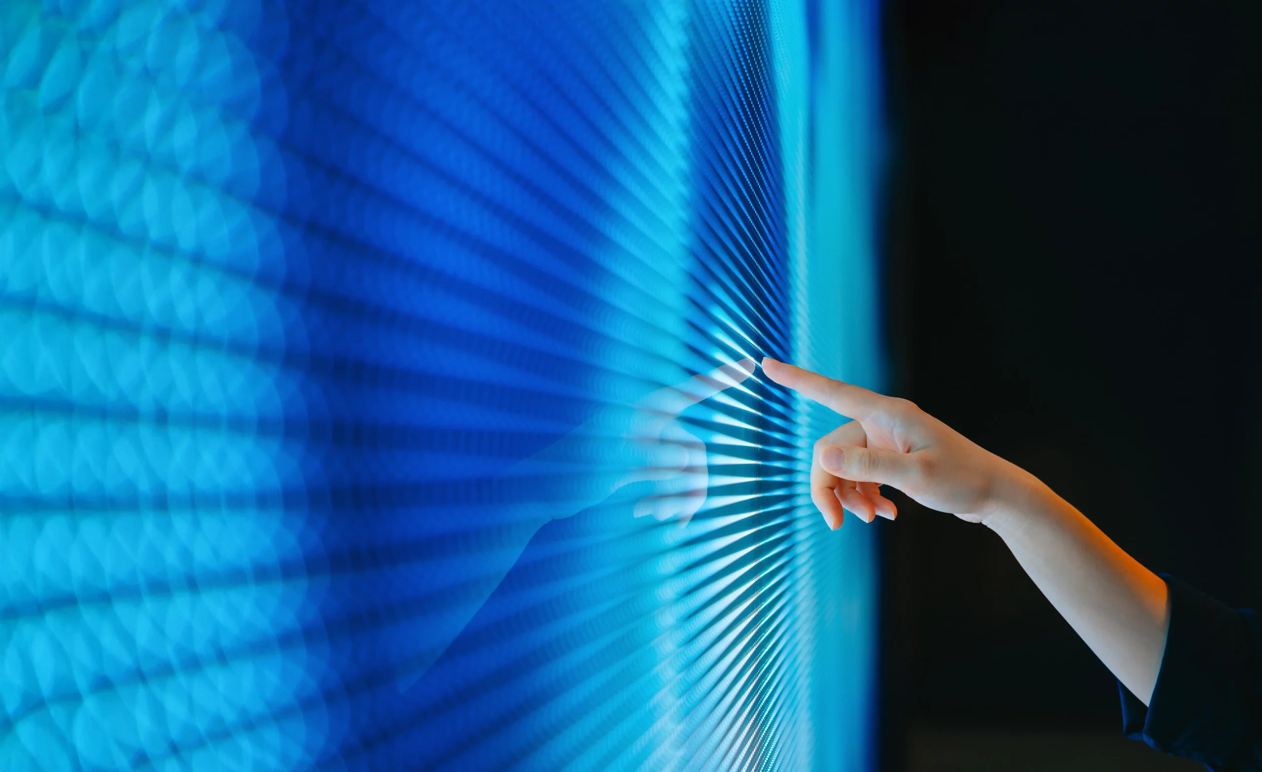 Human hand touching a blue digital interface, symbolizing the interaction between human judgment and AI technology.